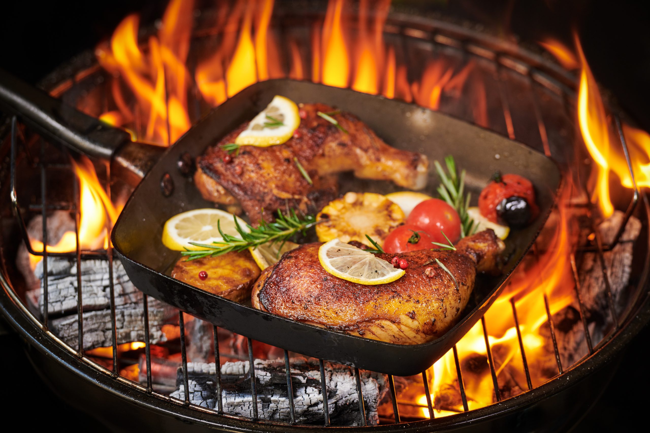 Grilled chicken legs on the flaming grill with grilled vegetable